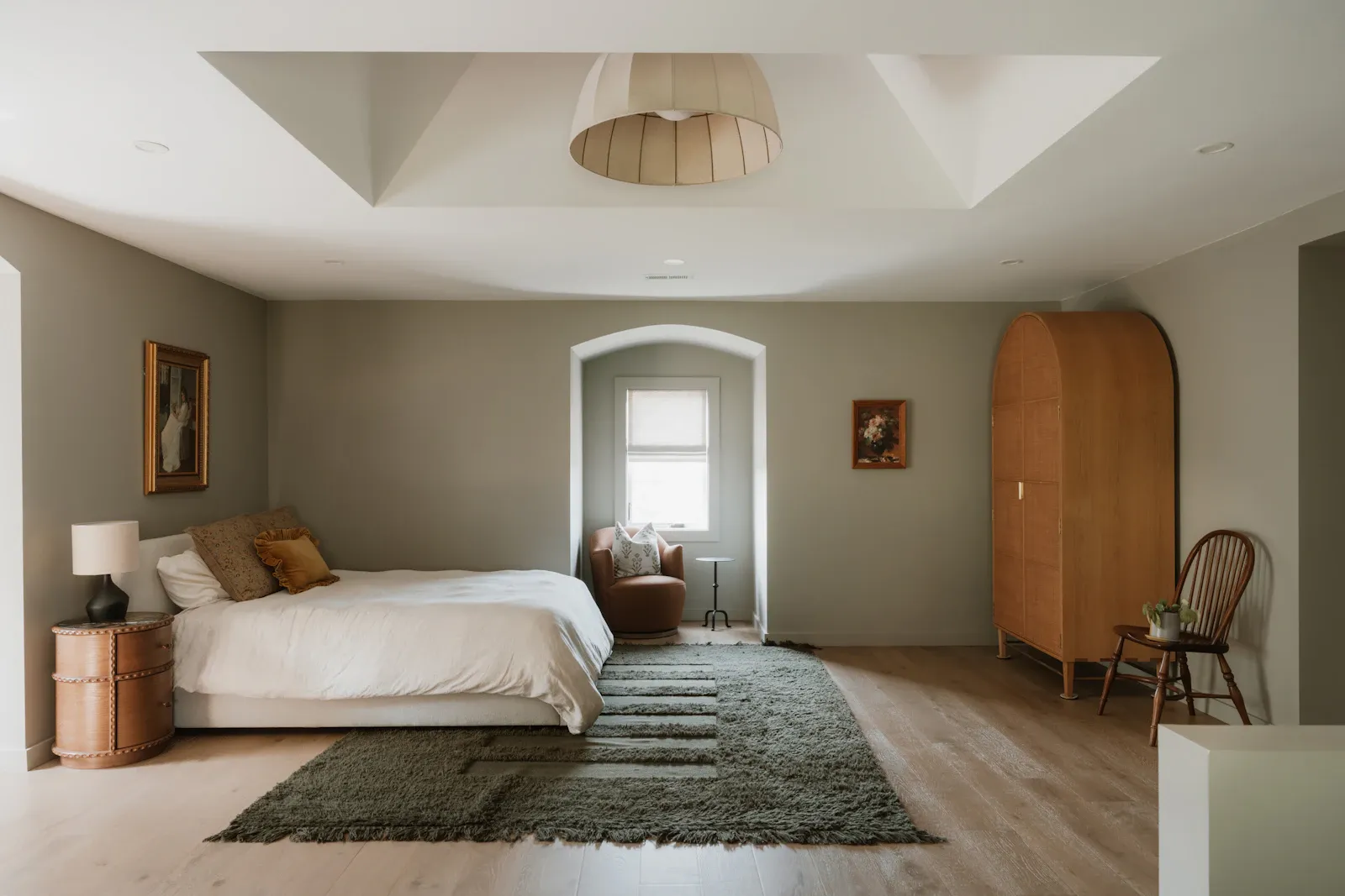 A neutral bedroom with a large bed and warm wood details