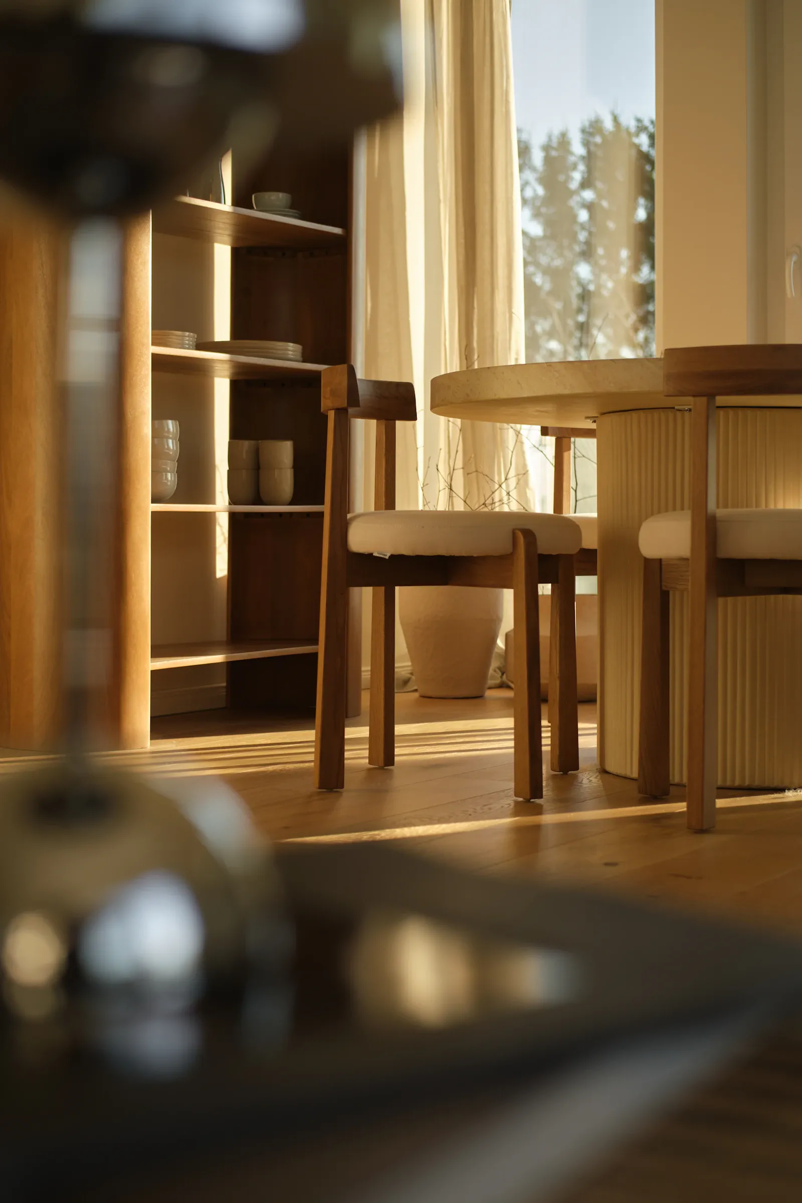 A sunlit modern dining room with warm wood chairs